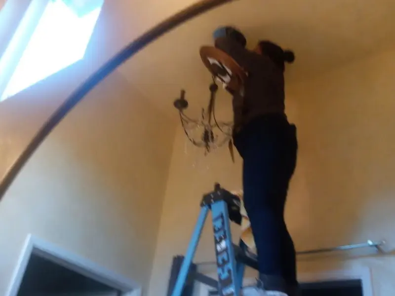 Electrician installing a chandelier in a Frontenac residence